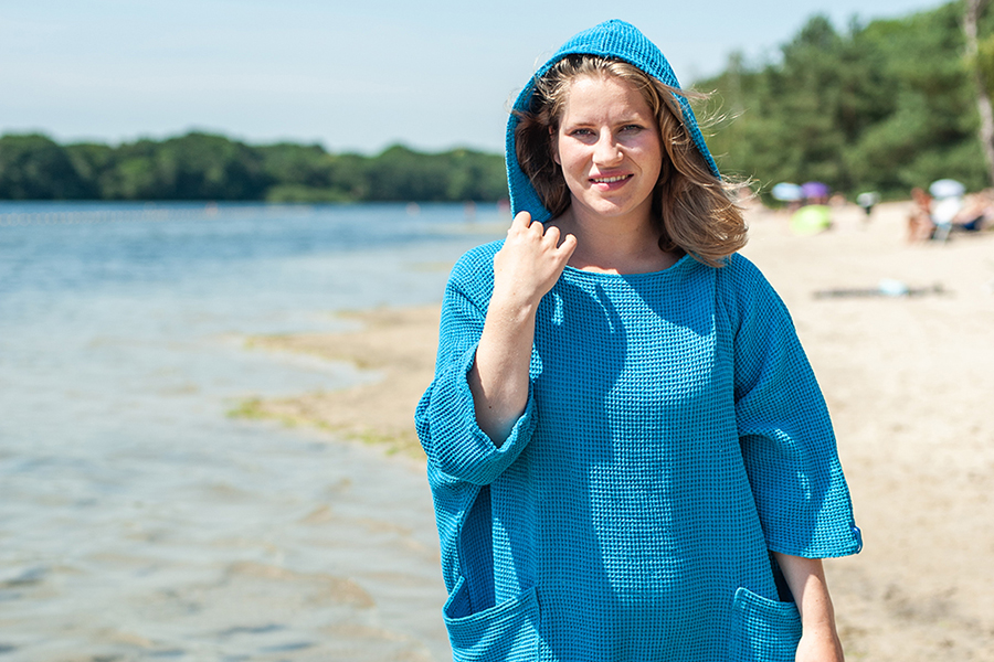 Vrouw in een zeemeermantel aqua blue. De zeemeermantel is een mooie en handige omkleedponcho